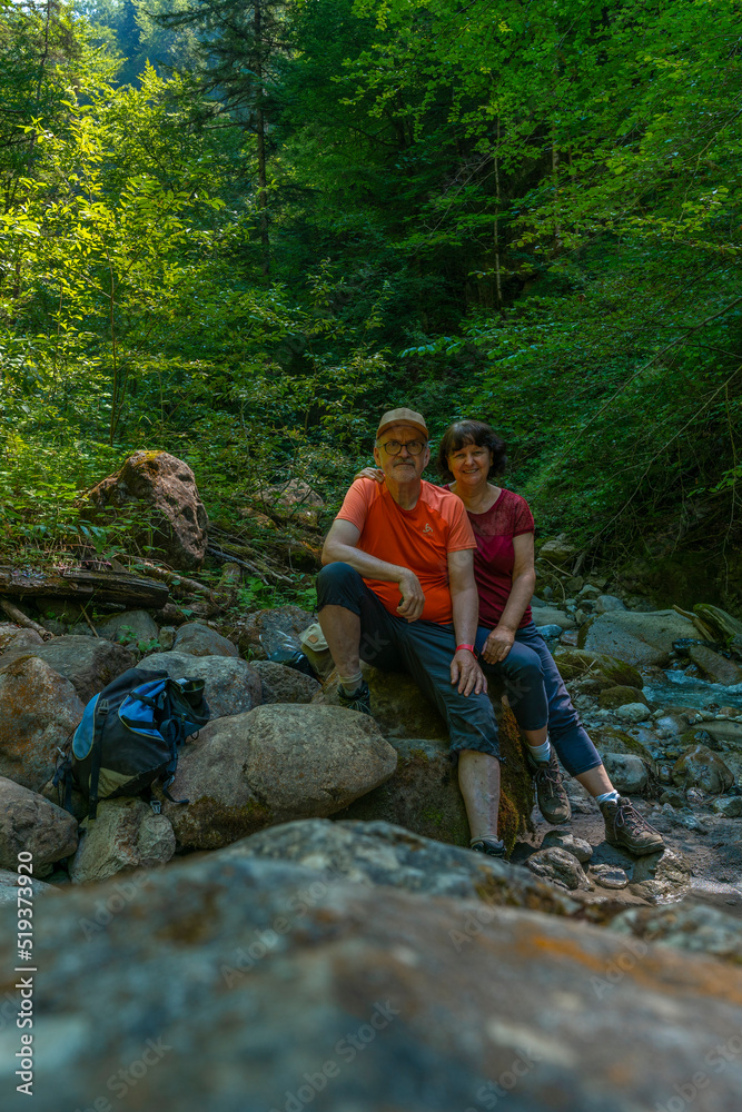 Ein Paar macht an einem heißen Sommertag ein Selfie in einem kühlen Bachbett. Ein Mann und eine Frau sitzen zwischen Felsen im Tal, Wanderer unterwegs im Schatten