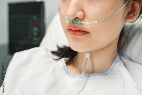 Close-up shot of young Asian woman wearing nasal cannula spending day in emergency room after accident
