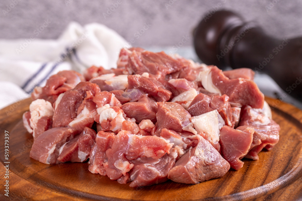 Lamb cubed meat. Chopped red meat in a wooden serving dish on a stone background. Butcher products. close up Lamb cubed meat. Chopped red meat in a wooden serving dish on a stone background. Butcher products. close up