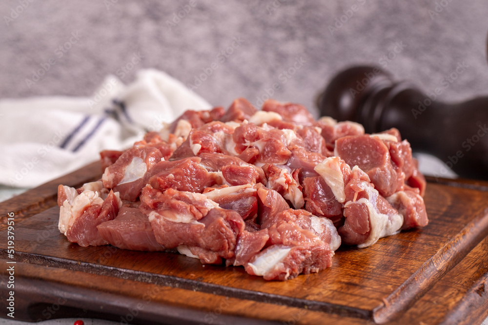 Lamb cubed meat. Chopped red meat in a wooden serving dish on a stone background. Butcher products. close up