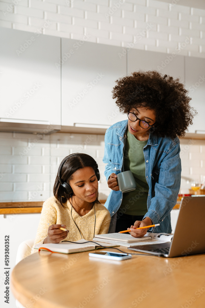 African american woman and daughter doing homework together at home African american woman and daughter doing homework together at home