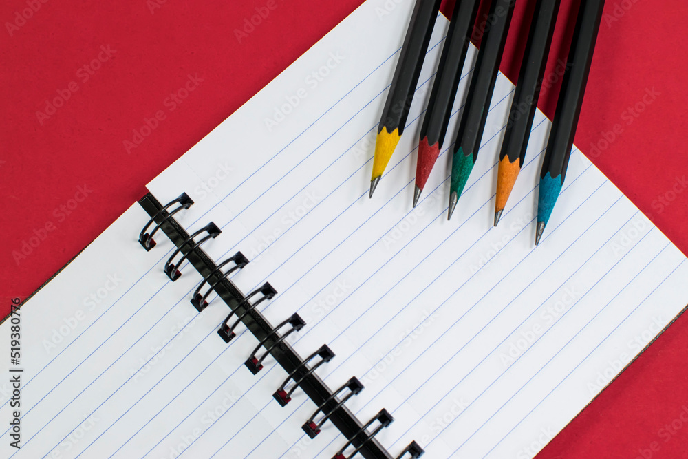 Top view notebook and colour pencil accessories studying in the library at school red background idea education Top view notebook and colour pencil accessories studying in the library at school red background idea education
