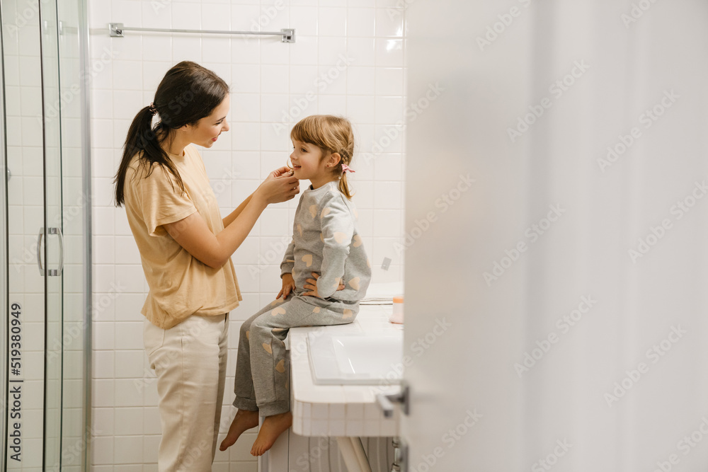 White woman smiling while talking with her daughter in bathroom White woman smiling while talking with her daughter in bathroom