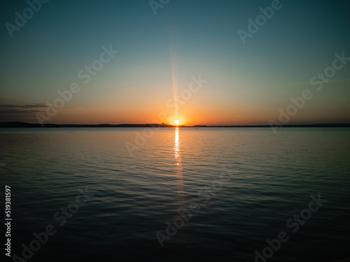 Atmospheric phenomenon sun column.Sunset over the lake. Evening summer landscape.