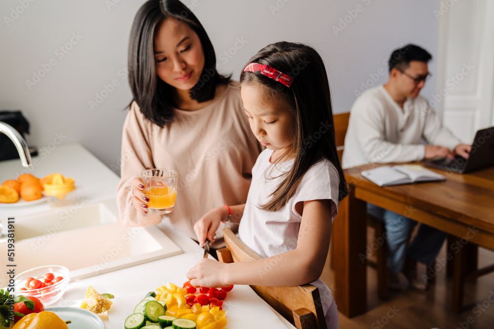 Happy asian family cooking and working on laptop at home Happy asian family cooking and working on laptop at home