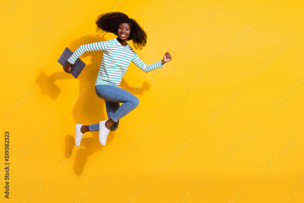 Full size profile photo of energetic excited person hold netbook hurry jump run empty space isolated on yellow color background