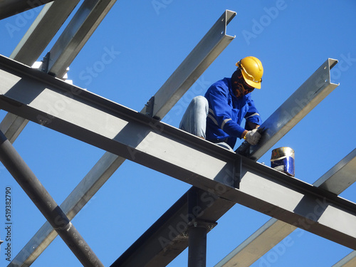 Photography SELANGOR, MALAYSIA -JUNE 16, 2021: Construction workers install trusses and roofing sheets at construction sites