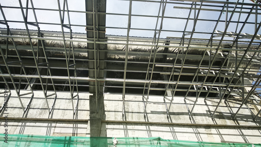 SELANGOR, MALAYSIA -JUNE 16, 2021: Construction workers install trusses and roofing sheets at construction sites. Lightweight roof trusses used are more economical, sturdy and fast.