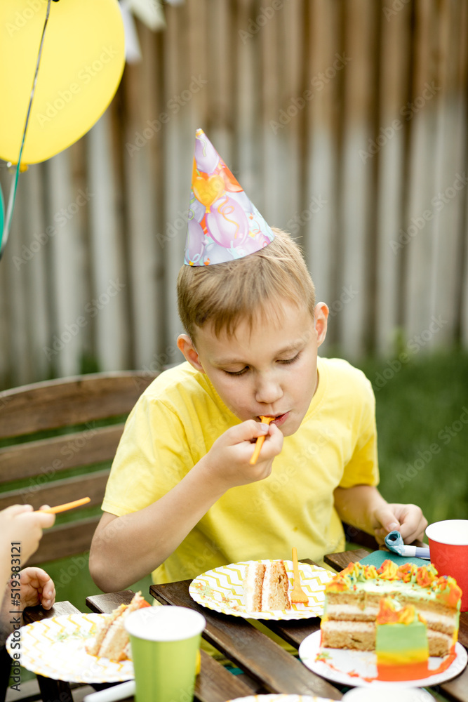 Cute funny nine year old boy celebrating his birthday with family or friends and eating homemade