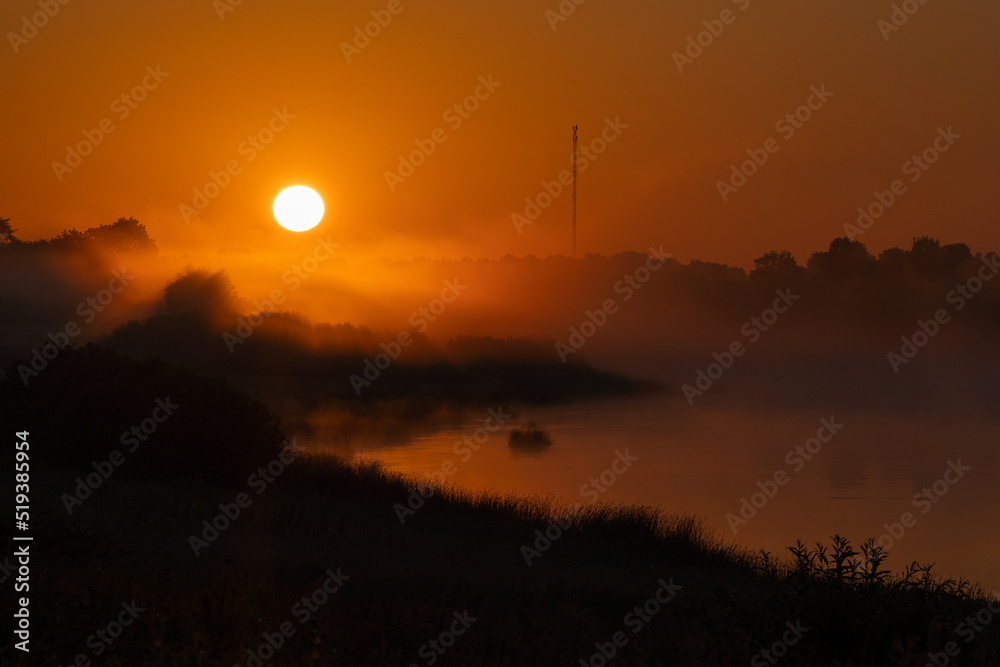 Fototapeta premium Beautiful and amazing sunrise over the river in fog