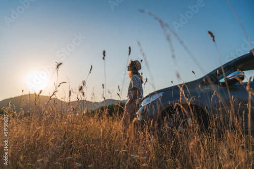 Obraz na płótnie Young beautiful woman traveler enjoying the sunset in the mountains while traveling by car w salonie