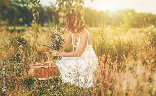 Fototapeta Naklejka Na Ścianę i Meble -  Woman collects beautiful spring flowers in a summer day.