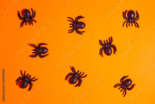 Many plastic spiders on orange background © Nando Vidal