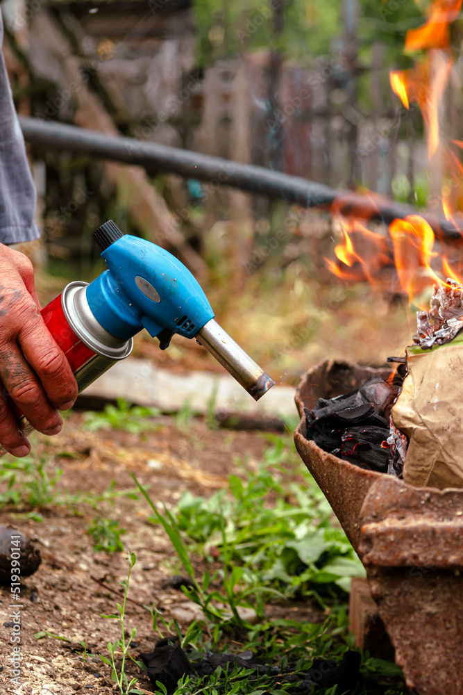 Fototapeta premium Ignition with a burner. A man sets fire to firewood with a gas burner.