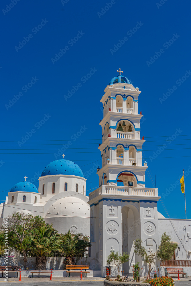Greek church bell tower, Timiou Stavro in Perissa on Santorini, background the church of the Holy Cross, vertical