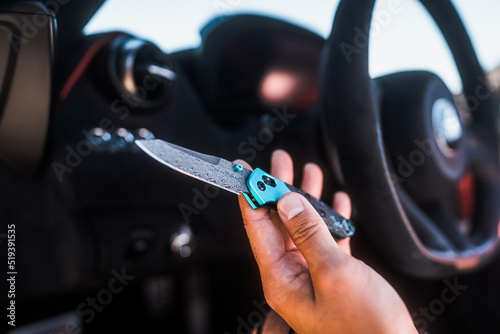 Showing a open Damascus blade pocket knife in front of a steering wheel photo