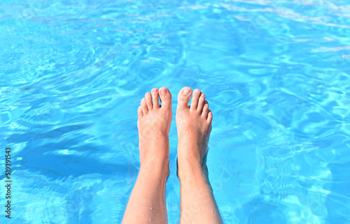 A woman with bare feet above the blue water of a swimming pool