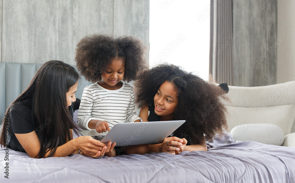 Portrait of an Asian mother with a multi-ethnic daughter Two cute little girls using laptops searching for friends to study.