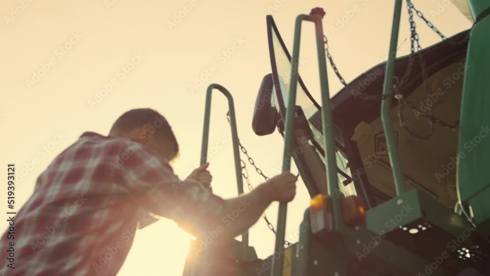 Driver go tractor cabin at sunset. Professional agronomist working on harvesting