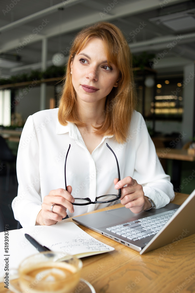 Young woman in eyeglasses and white shirt sitting in a public place Young woman in eyeglasses and white shirt sitting in a public place
