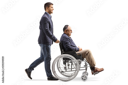 Full length profile shot of a son walking and pushing a mature man in a wheelchair