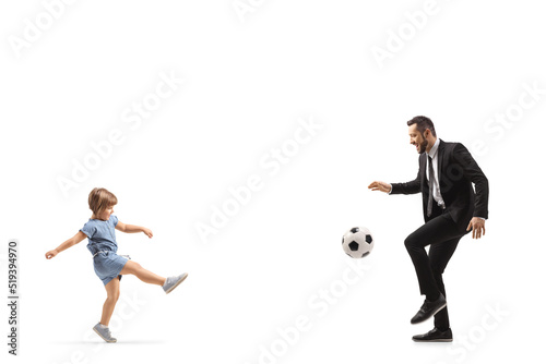 Full length profile shot of a little girl kicking a football to her father