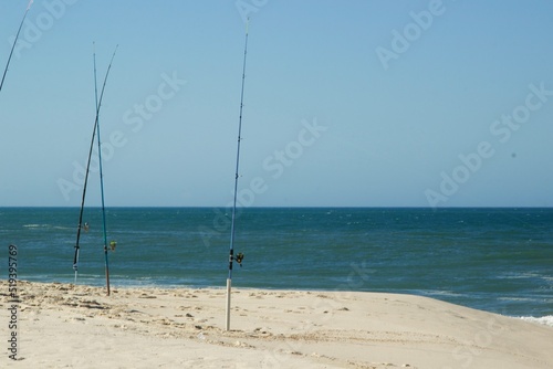 Varas de pescar - fishing rods - Fisherman setting up fishing rods on sea beach, seaside landscape