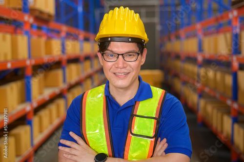 Portrait of young asian male worker wearing helmet in modern warehouse storage of retail shop