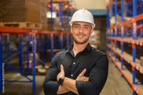 Portrait of young caucasian male worker wearing helmet in modern warehouse storage of retail shop