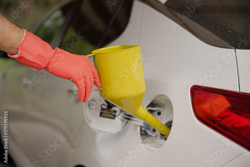 The man keeps a can for pouring gasoline from the canister into the car. Yellow watering can in the fuel holes. Gasoline collapse. Alternative fuelling method © Alex