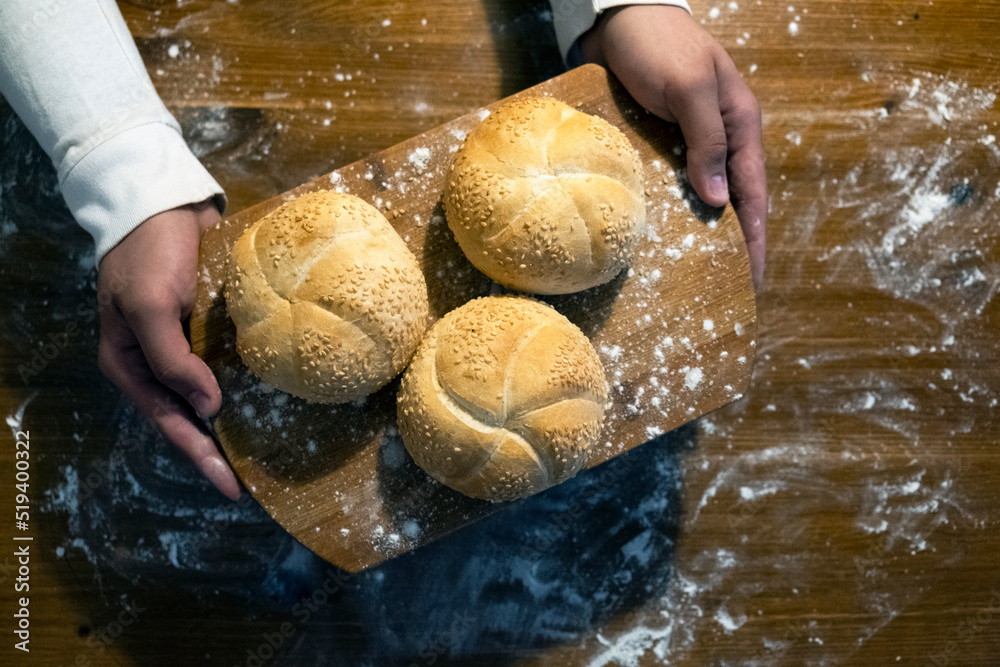 man board with buns with sesame top view. Flour is scattered on the table. The man made buns. Buns for breakfast. Bakery products