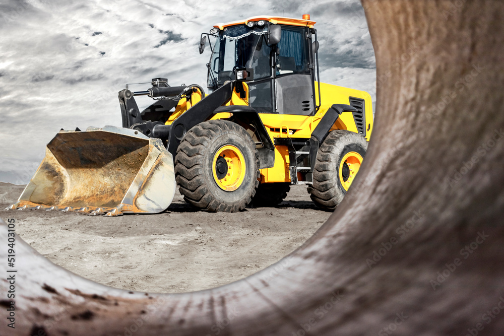 Bulldozer or loader moves the earth at the construction site against the sunset sky. Contrasting image of a modern loader or bulldozer. Construction heavy equipment for earthworks.