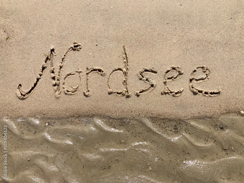 Fototapeta premium Schrift Nordsee am Strand bei ablaufendem Wasser / Ebbe