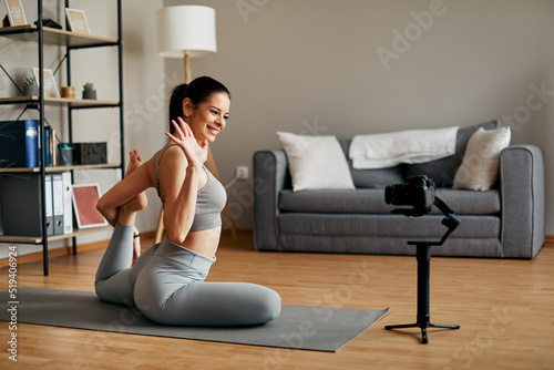 Young woman recording a yoga tutorial exercises at home