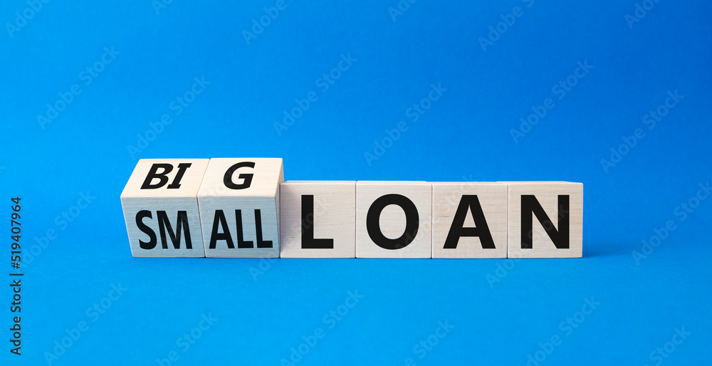 Big loan and Small loan symbol. Turned cubes with words Small loan and Big loan. Beautiful blue background. Busines concept. Copy space
