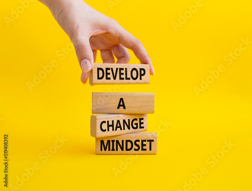 Develop a change mindset symbol. Concept words Develop a change mindset on wooden blocks. Beautiful yellow background. Businessman hand. Business and Develop a change mindset concept. Copy space. © Natallia