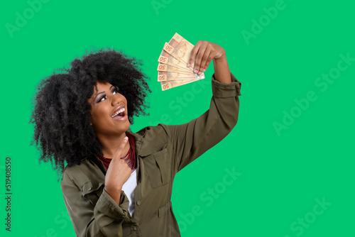 woman holding money, young smiling woman holding Brazilian money, green background photo