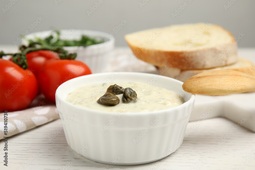 Creamy caper sauce in bowl on white wooden table, closeup Creamy caper sauce in bowl on white wooden table, closeup
