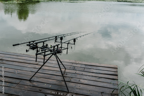 Spinning. Fishing with signaling devices on holder. Feeder fishing with reel. Rod pod. Fishing rods for pike, perch, carp on pond. Angler with fishing technique. World Fisherman's Day, photo article.