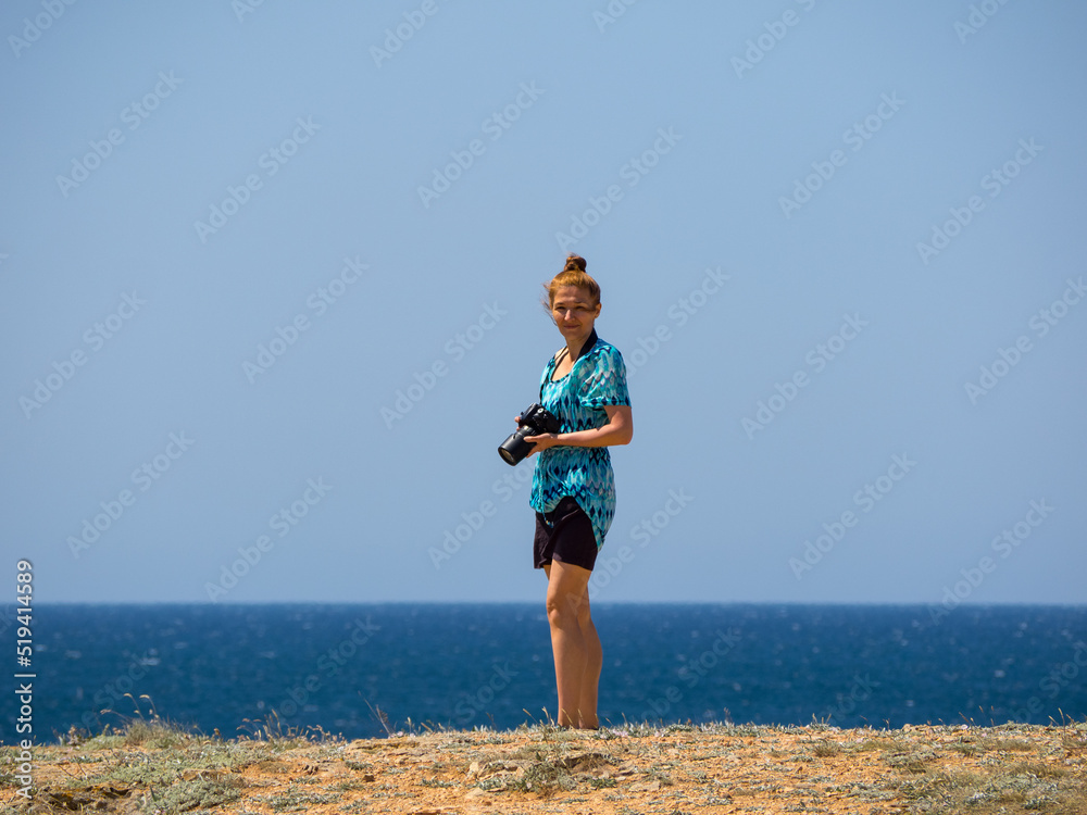 Happy smiling woman with photo camera on blue sea background. The concept of vacation, travel, active tourism