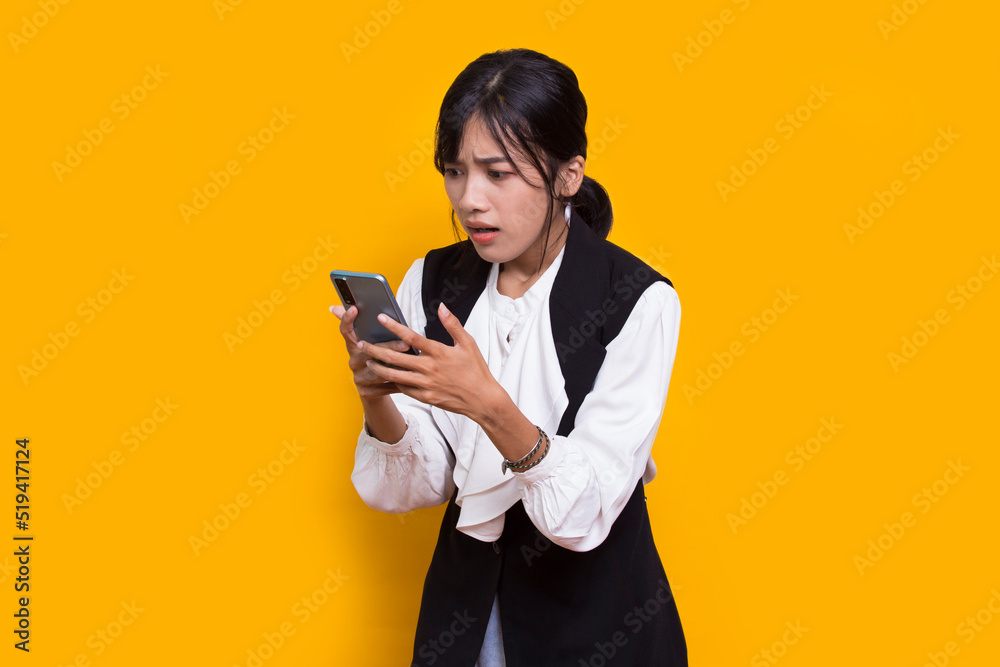 mad and shock young asian beautiful woman using mobile phone isolated on yellow background mad and shock young asian beautiful woman using mobile phone isolated on yellow background
