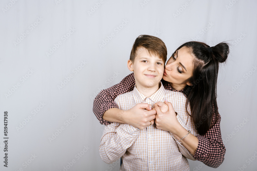 Parenting teen boys, Raising a teen. Studio portrait of Happy Teen boy hugging his mom Parenting teen boys, Raising a teen. Studio portrait of Happy Teen boy hugging his mom