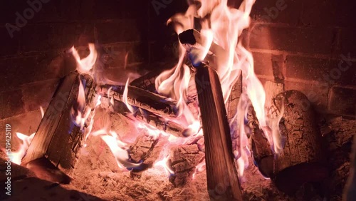 Cold winter and heating the house with firewood and coal in the fireplace. Red and orange flames in the fireside with bricks. Calm and romantic atmosphere at the evening in the warm home. photo