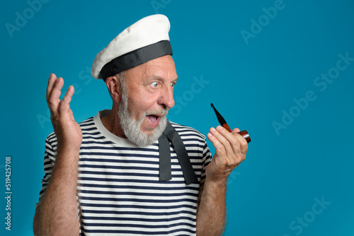 Wow. Old sailor portrait Surprise and admiration. Smoking pipe, marine form. on a blue background isolated