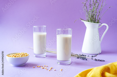 Vegan pea or plant-based lavender milk in glasses, pea seeds, white jug with lavender, yellow napkin. Lilac background. Copy space photo