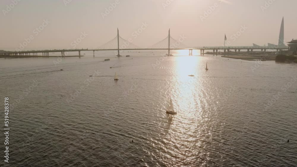 Cable-stayed bridge at sunset, car traffic on the highway over water, magic reflection of sun in water, water navigation, boats and yachts Cable-stayed bridge at sunset, car traffic on the highway over water, magic reflection of sun in water, water navigation, boats and yachts