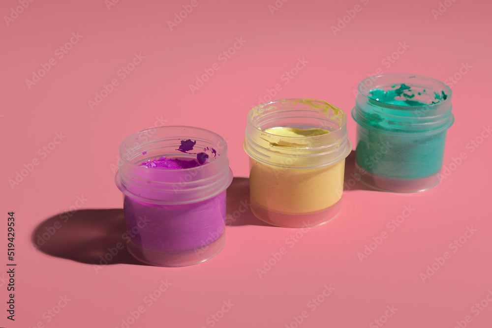 three open jars with acrylic paint on a colored background three open jars with acrylic paint on a colored background