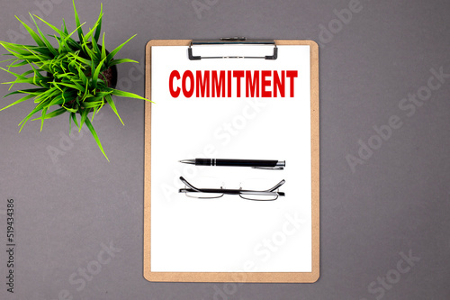 COMMITMENT on the brown clipboard on the grey background. Business concept photo
