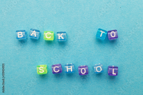 The inscription back to school made by multicolor plastic cubes on a blue background.
