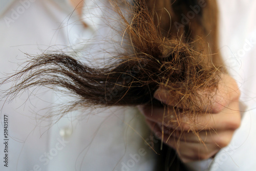 The girl holds the ends of damaged dry hair in her hand. Hair close-up.